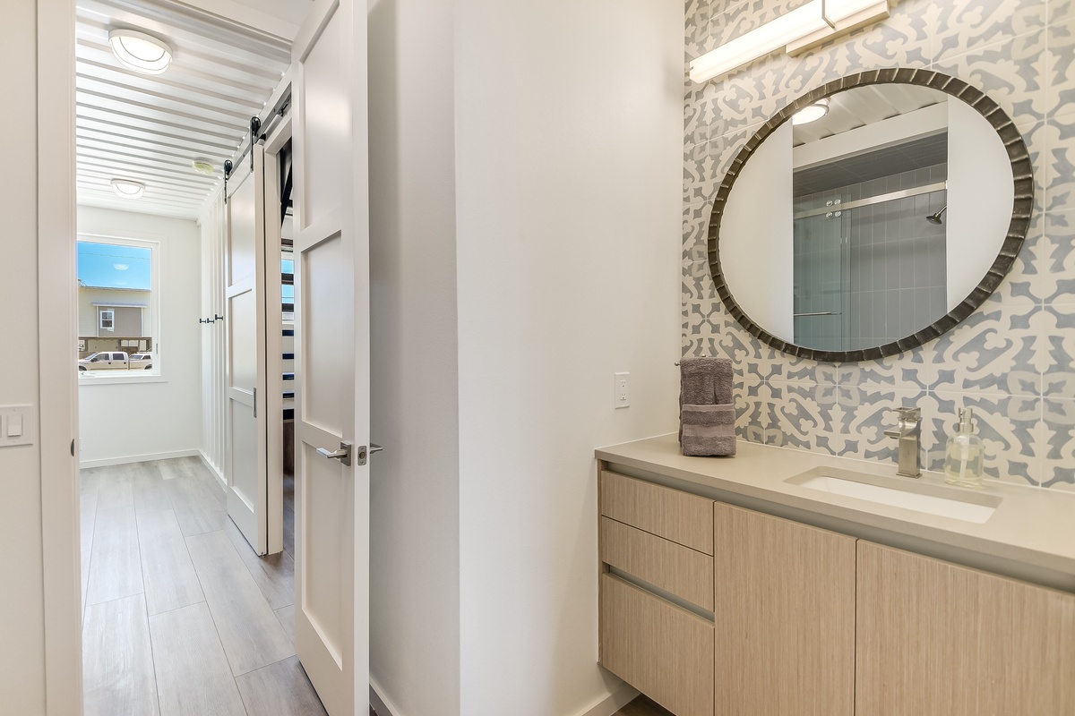 Your stylish powder room features a stunning patterned accent wall and modern vanity, perfect for freshening up.