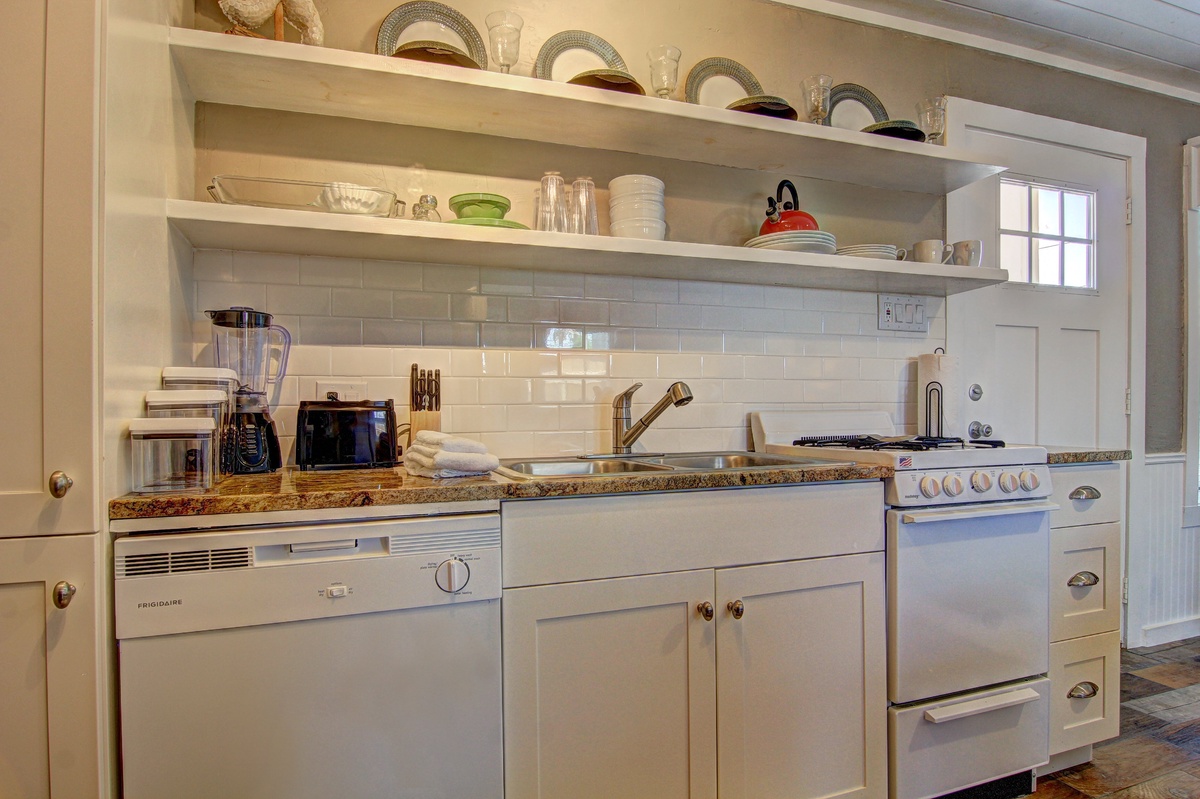 Your charming kitchen awaits with granite counters, subway tile backsplash, and open shelving displaying vintage plates—perfect for morning coffee rituals.