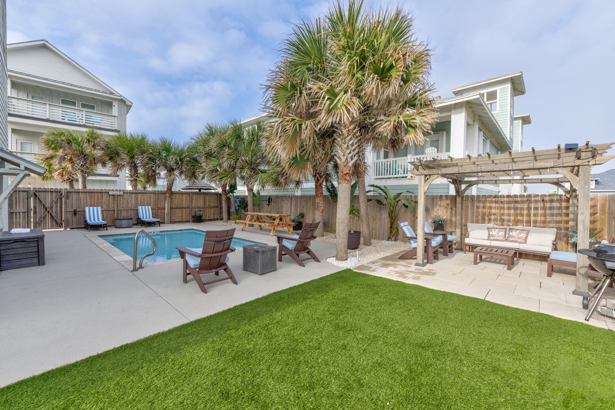 Your private oasis awaits with a sparkling pool, shaded pergola, and lush lawn perfect for lounging under swaying palms.