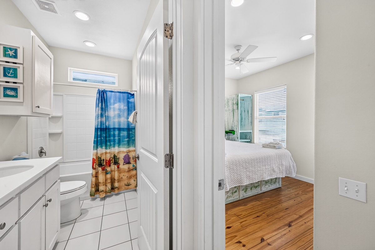 Step into your bright coastal retreat where a bedroom and ensuite bathroom await. Notice the charming nautical touches and warm wood floors that welcome you home after sun-soaked beach days.