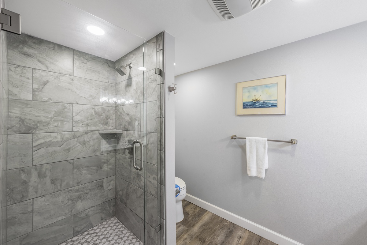 Your private bathroom features a stunning marble-tiled walk-in shower with glass doors, perfect for refreshing after coastal adventures.