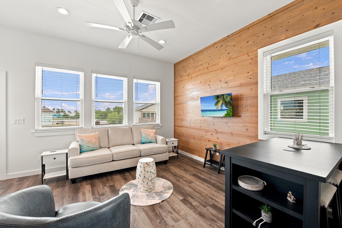 Relax in your bright, cozy living room with warm wood accents and plenty of natural light. Unwind on the sofa, enjoy the ceiling fan, and make yourself at home.