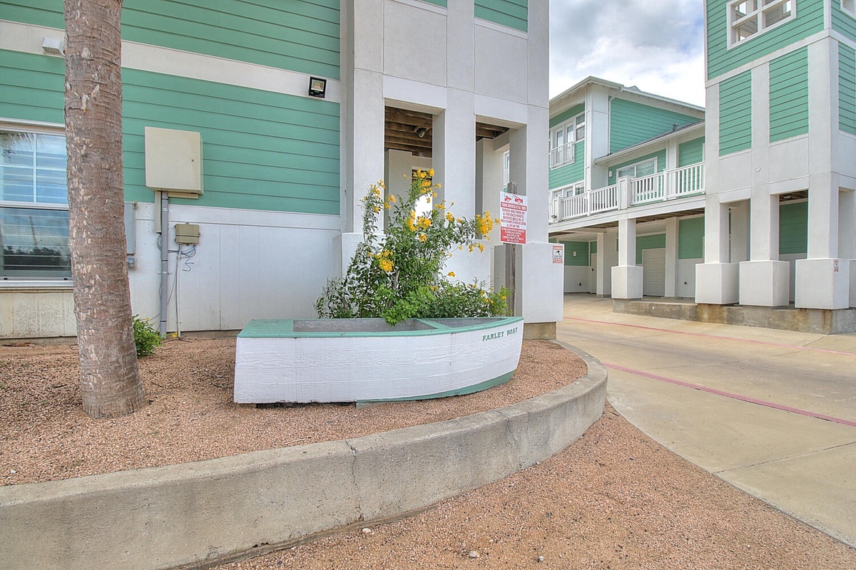 Charming beachside property with tropical landscaping and covered entrance featuring coastal-style architecture in relaxing turquoise tones.
