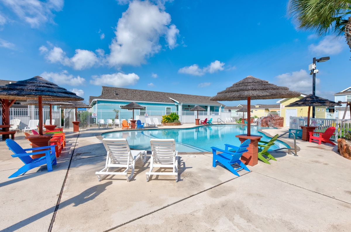 Bright blue pool with colorful lounge chairs and tropical umbrellas under sunny skies—perfect for relaxing poolside days.