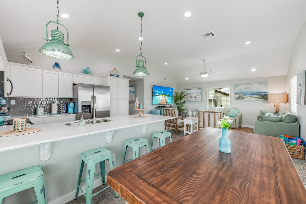 Your spacious open-concept living area features a fully-equipped kitchen, cozy dining space, and relaxing lounge with coastal-inspired mint green accents throughout.