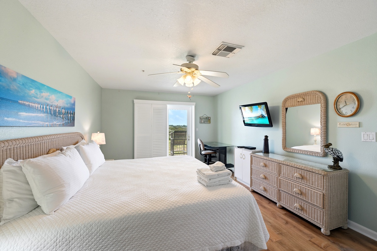 Sink into crisp linens and coastal charm, with natural light streaming through your private balcony doors. Rattan accents and gentle seafoam walls create a breezy, beachside retreat perfect for unwinding after your adventures.