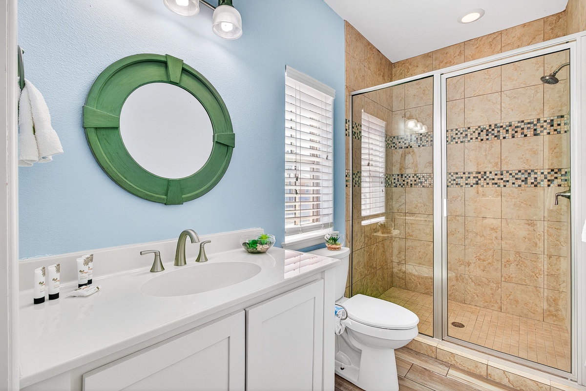Your private bathroom combines coastal charm with modern comfort, featuring a spacious walk-in shower and soothing blue walls.