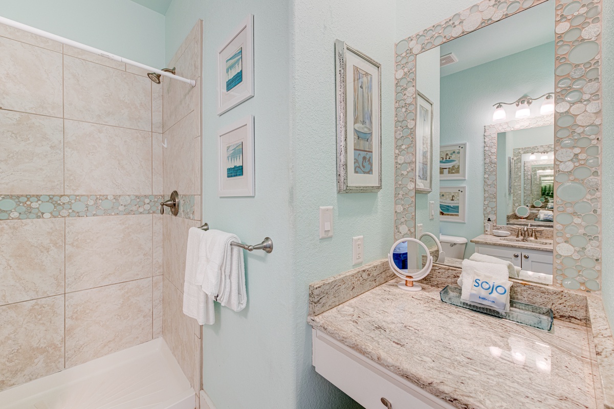 Unwind in your spa-inspired bathroom featuring elegant marble countertops, coastal artwork, and a refreshing tile shower perfect for morning rituals.