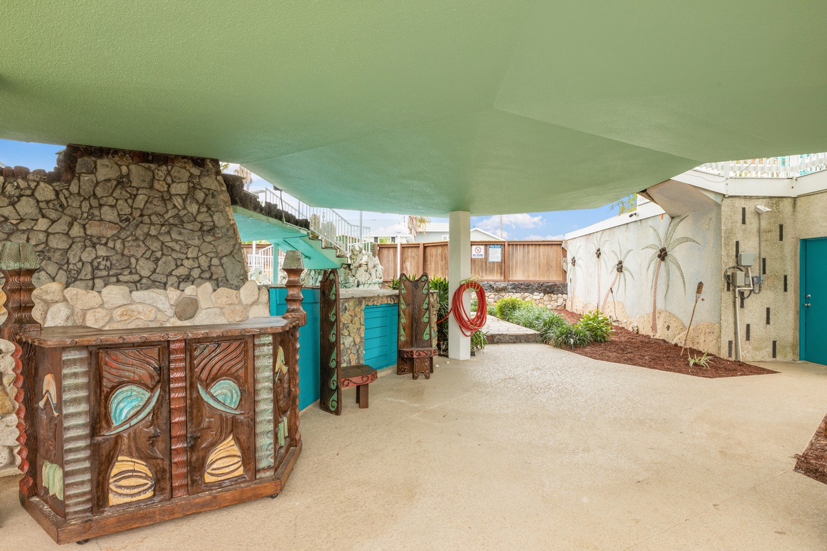 Your covered outdoor entertaining space features unique artistic touches, tropical plants, and plenty of room to gather and relax in style.