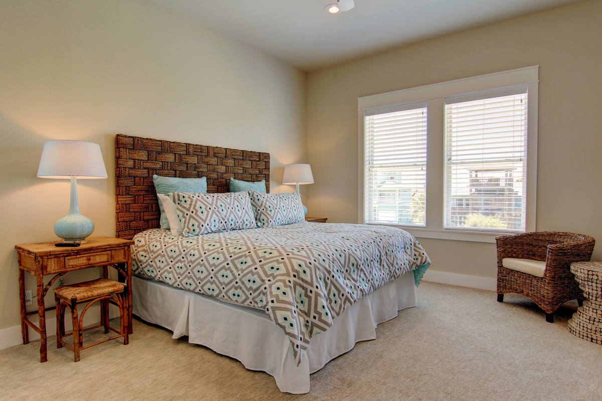 Sink into your plush bed with geometric linens and woven headboard. Natural light streams through windows while wicker accents create coastal charm.