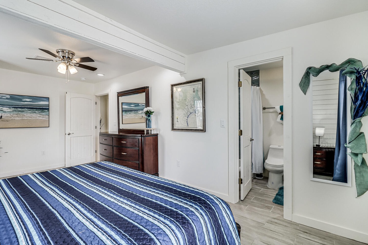 Unwind in your coastal-inspired bedroom with ocean artwork and exposed beams. The en-suite bathroom and stylish furnishings create your perfect retreat.
