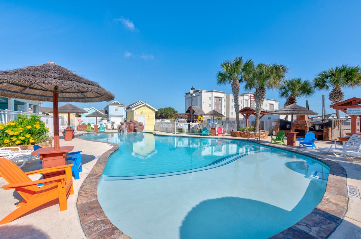 Dive into crystal-clear waters surrounded by colorful beach chairs and tropical palms in this vibrant resort-style pool area.