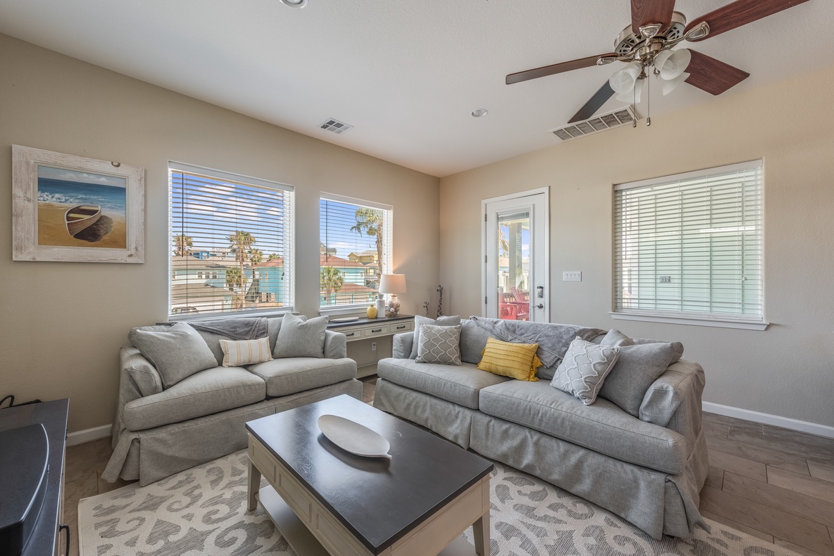 Sink into plush grey sectional seating where coastal artwork and palm-lined views create your perfect California retreat sanctuary.