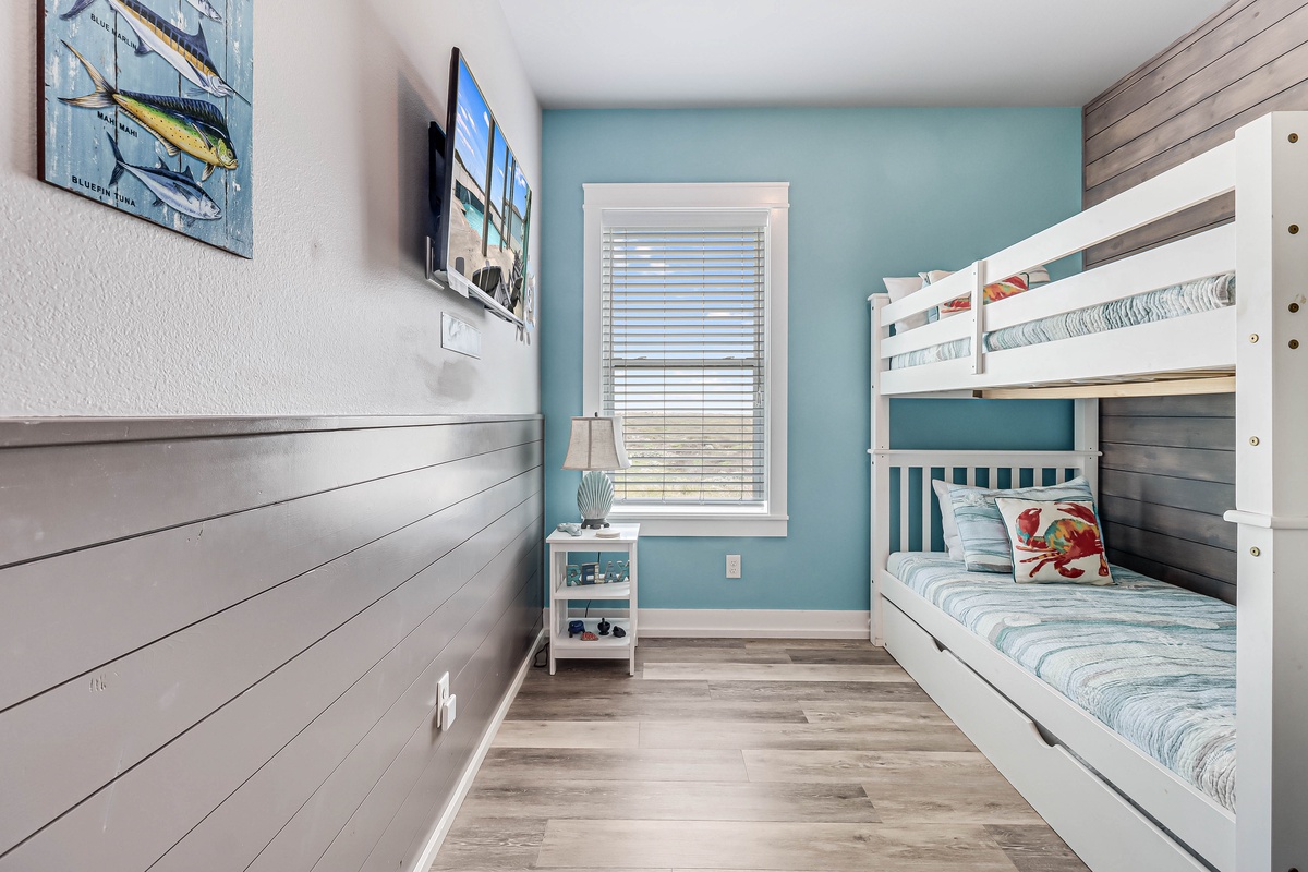 Your kids will love this coastal-themed bunk room with ocean hues and fun fish artwork creating the perfect beach getaway retreat.