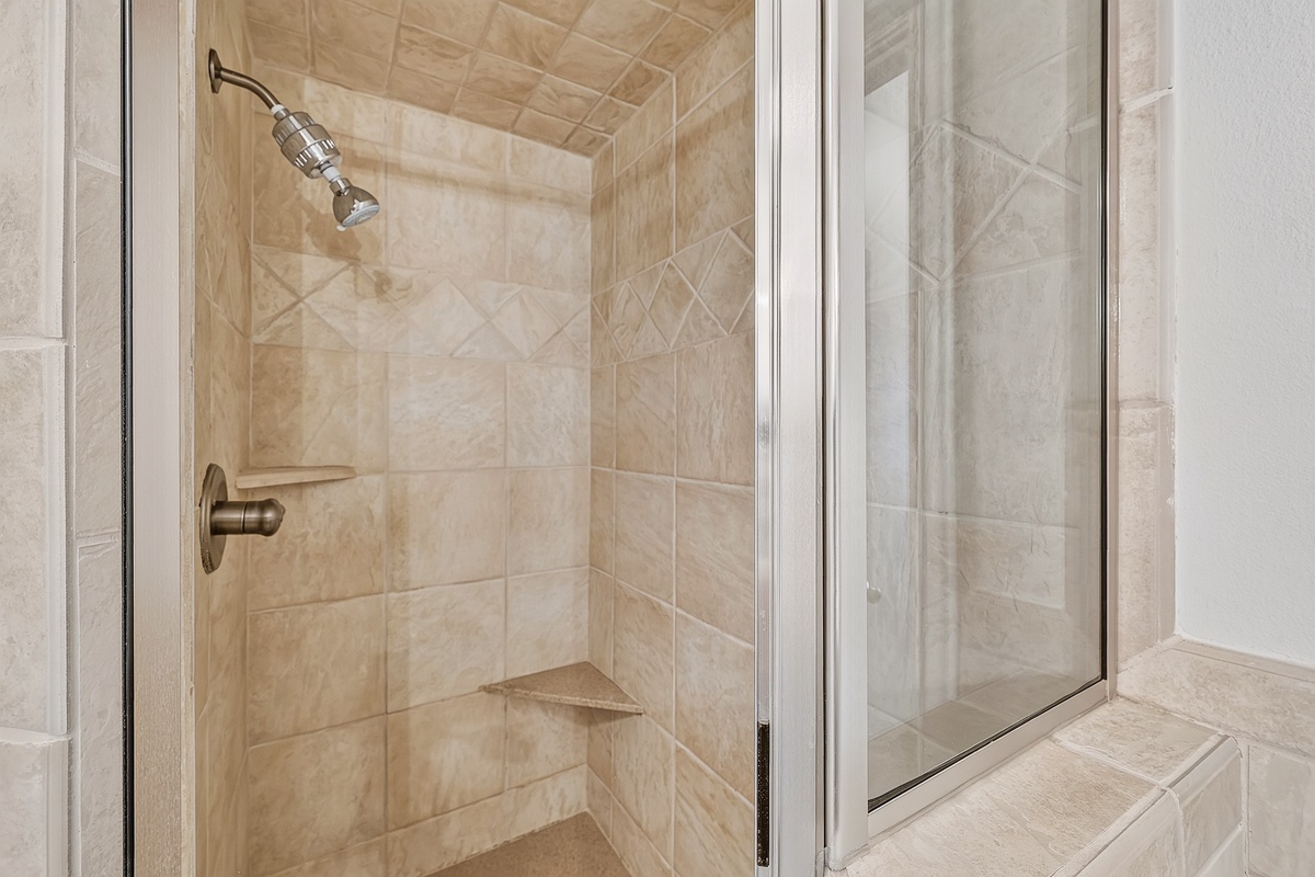 Step into a beautifully tiled walk-in shower with elegant stone finishes and a built-in corner seat. Your mornings just got more luxurious.
