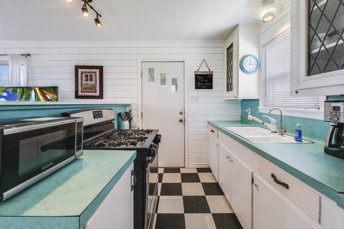 Step into your fully equipped kitchen with vintage charm—turquoise countertops, classic checkerboard floors, and modern appliances await your culinary adventures.