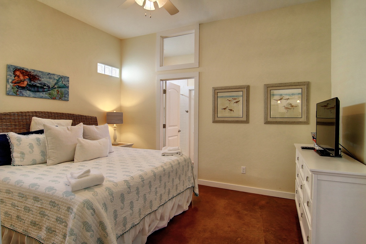 Retreat to your serene bedroom featuring warm nautical touches, a cozy bed with soft linens, and gentle ceiling fan for perfect comfort.