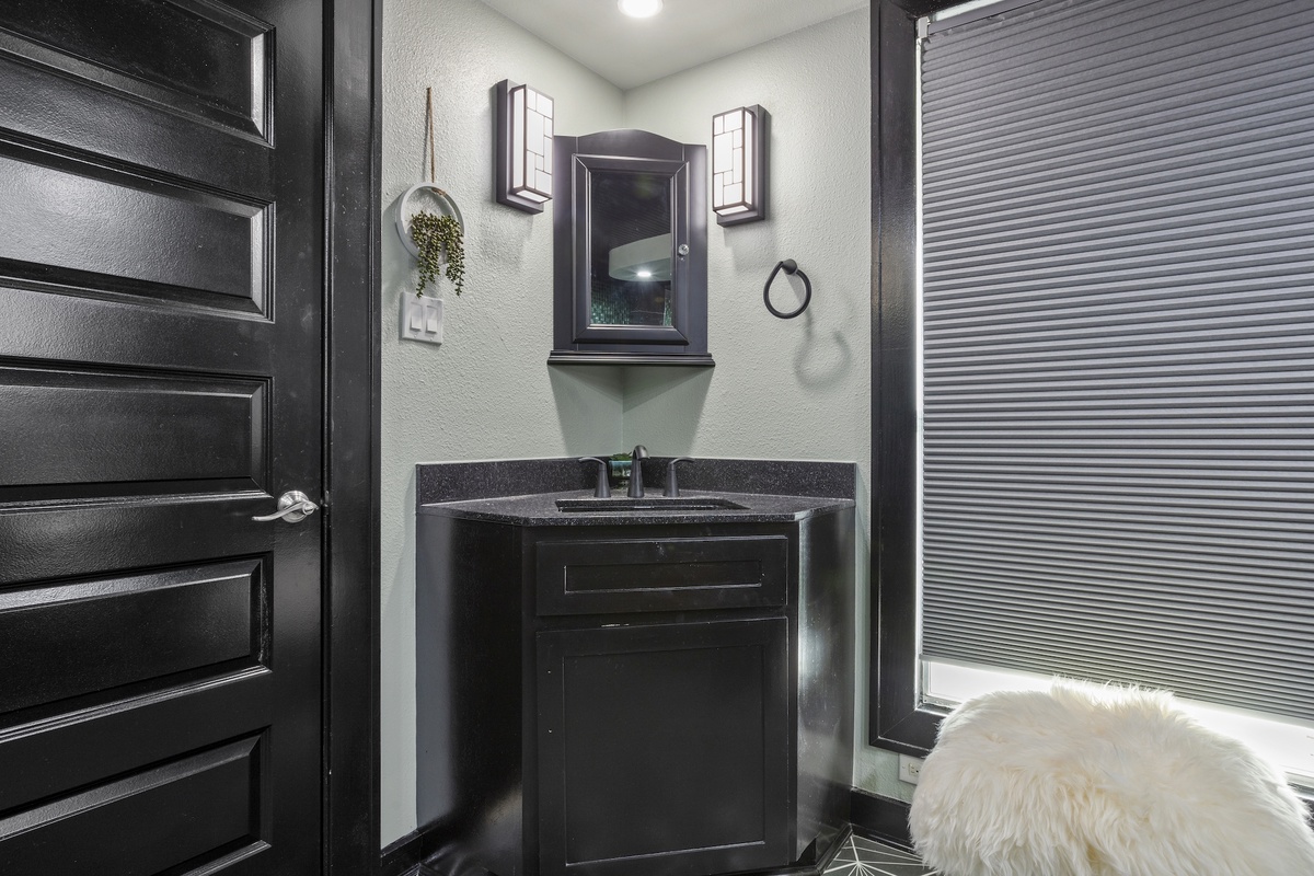 Your sleek powder room features modern dark cabinetry and stylish lighting for your convenience.