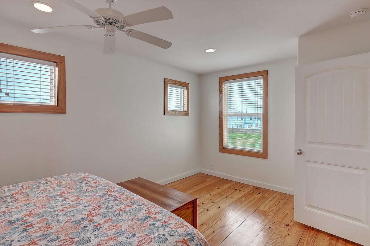 Rest peacefully in your bright bedroom with warm hardwood floors, ceiling fan, and cheerful windows overlooking the neighborhood.