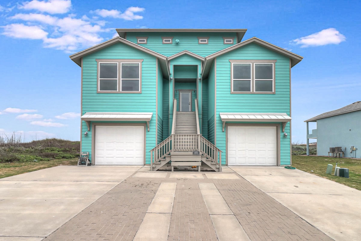 Charming turquoise beach house with spacious parking and elevated entrance, perfectly positioned in a coastal neighborhood.