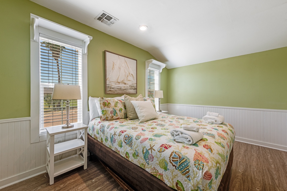 Rest peacefully in your bright bedroom with coastal charm, featuring comfortable bedding and nautical artwork for a serene coastal getaway.