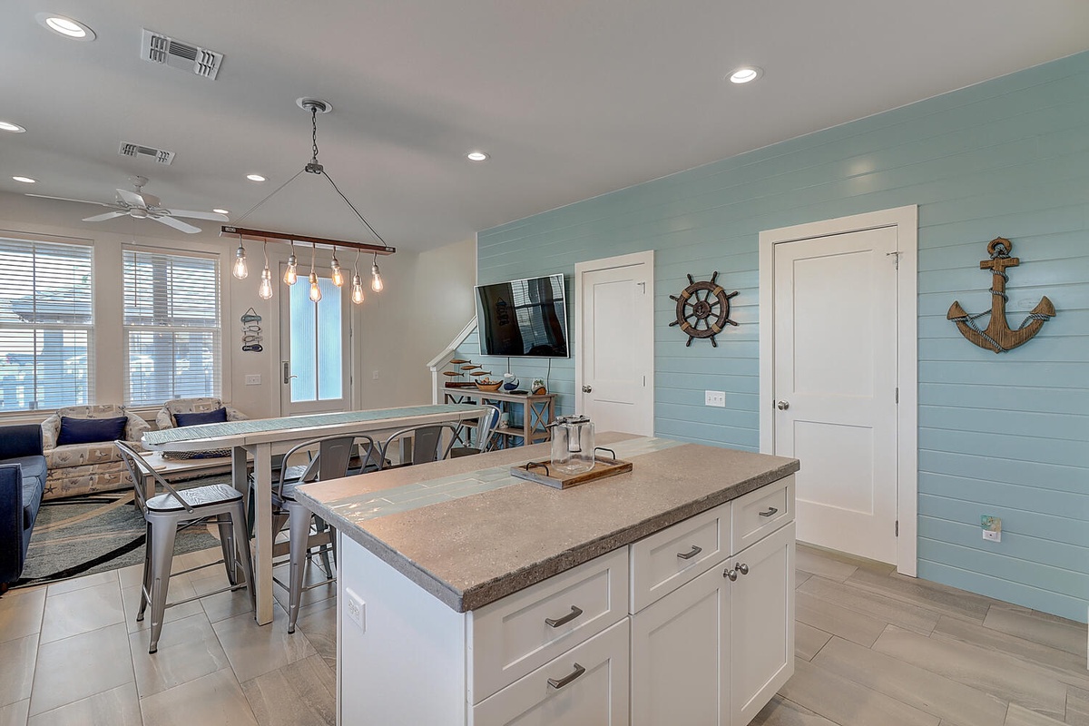 Your coastal-inspired kitchen island invites morning coffee while nautical touches and open living spaces create a relaxing beach house atmosphere.