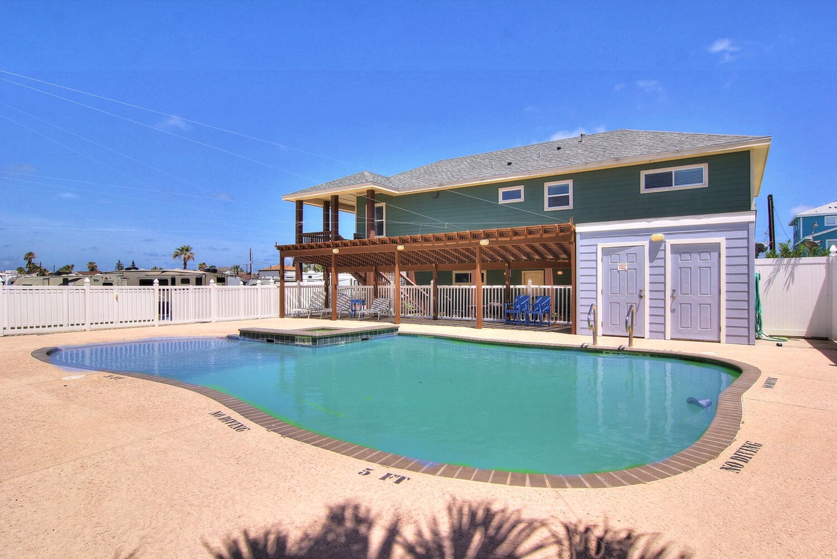 A sparkling pool awaits beneath clear blue skies at this charming coastal home with spacious deck and outdoor storage.