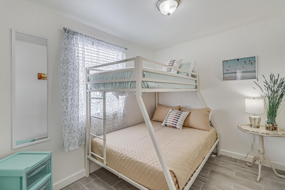 Your family's perfect retreat features a space-saving bunk bed setup where everyone sleeps comfortably in this bright, cheerfully decorated room.
