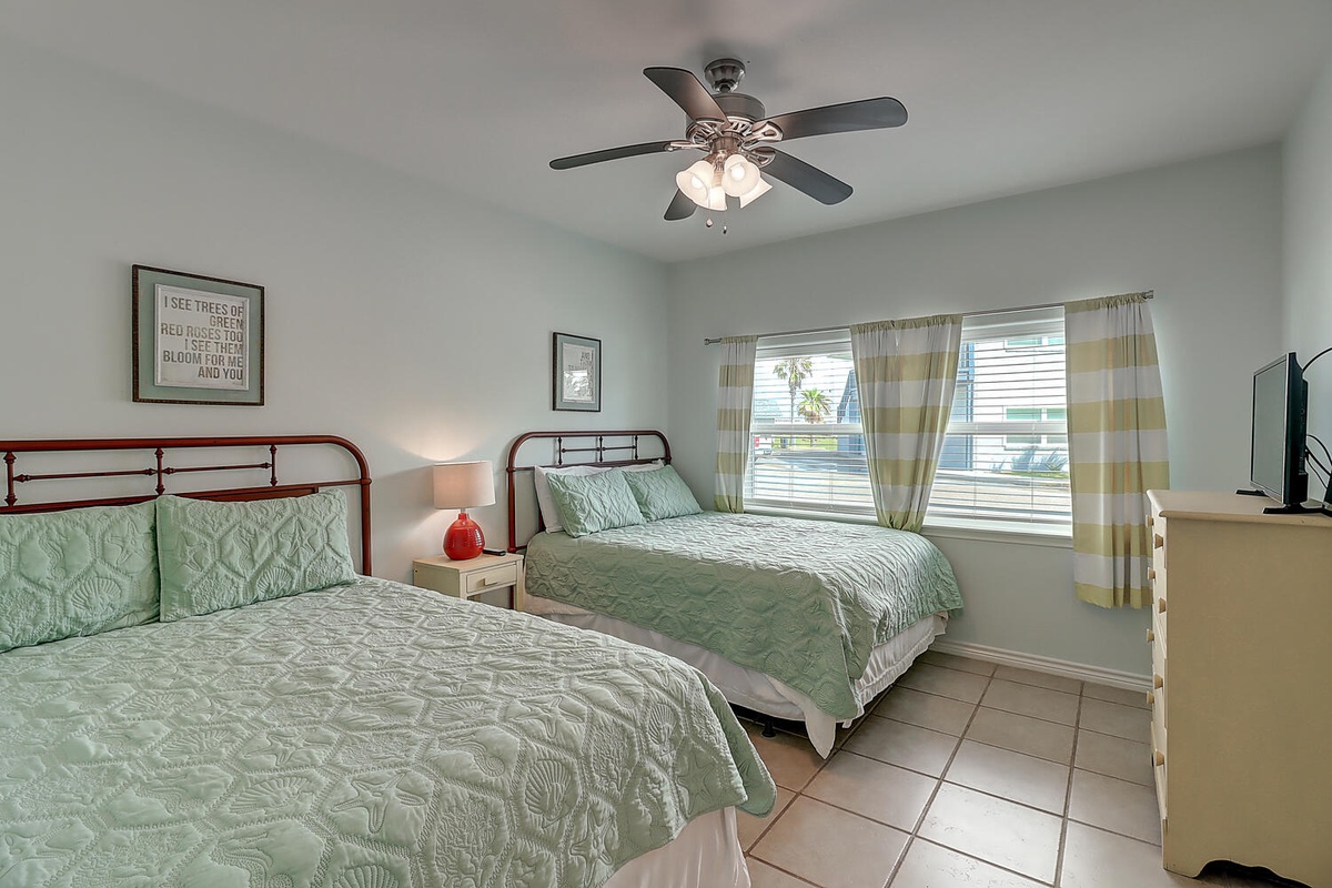 Your bright bedroom features two comfortable beds with tropical bedding and cooling ceiling fan for restful nights.