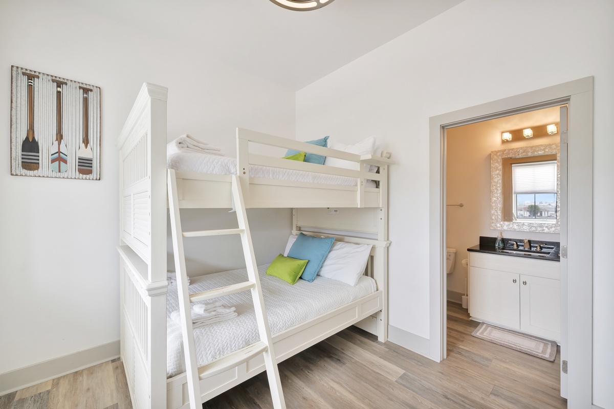 Your kids will love this bright bedroom with sturdy white bunk beds and colorful pillows, plus an ensuite bathroom for convenience.