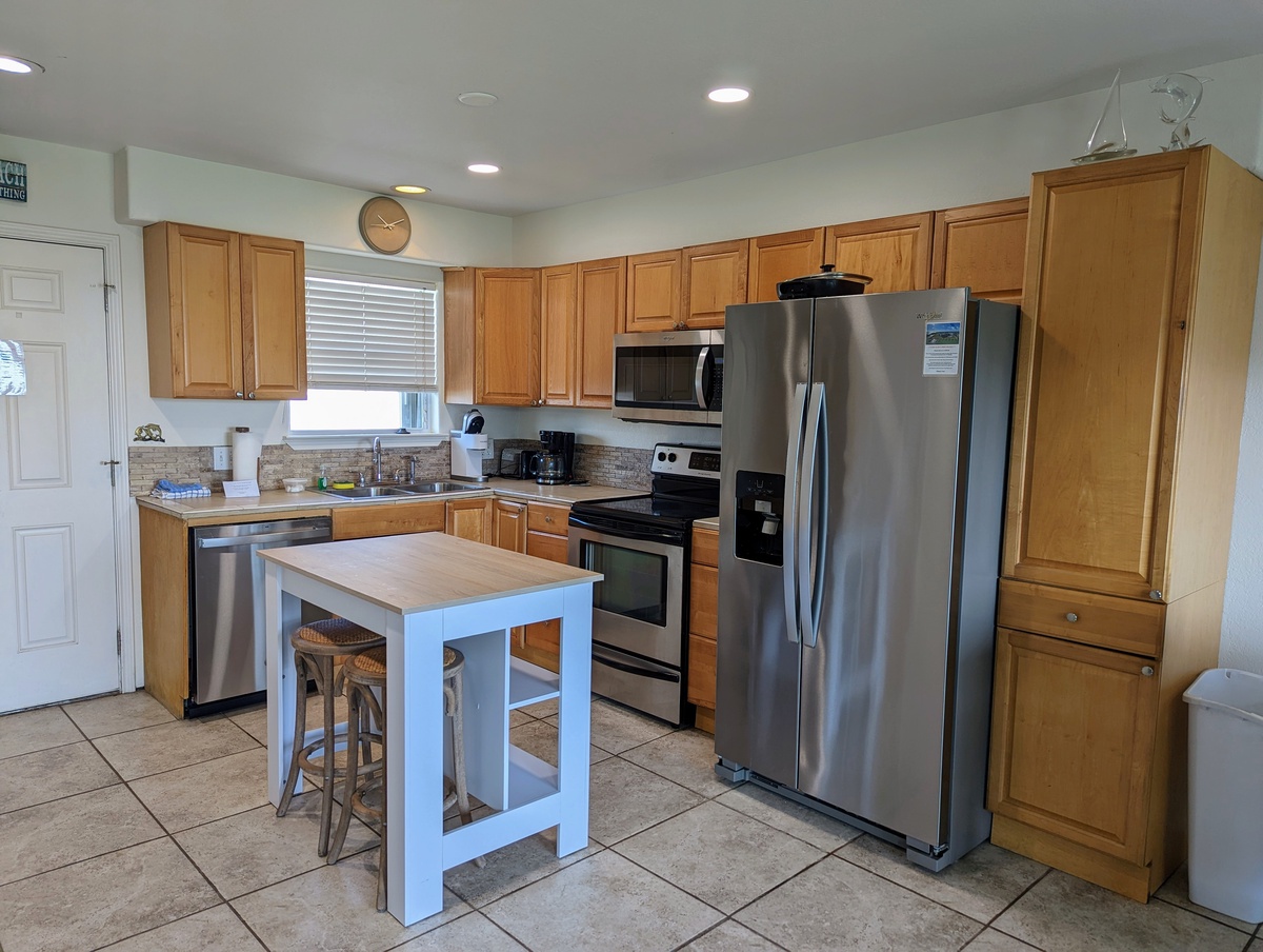 Your fully equipped kitchen awaits with stainless steel appliances, granite counters, and a charming breakfast island perfect for morning coffee.