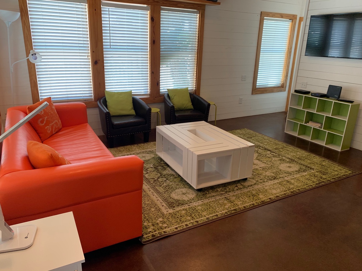 Settle into your bright living space featuring colorful seating, natural light, and entertainment center for cozy evenings.