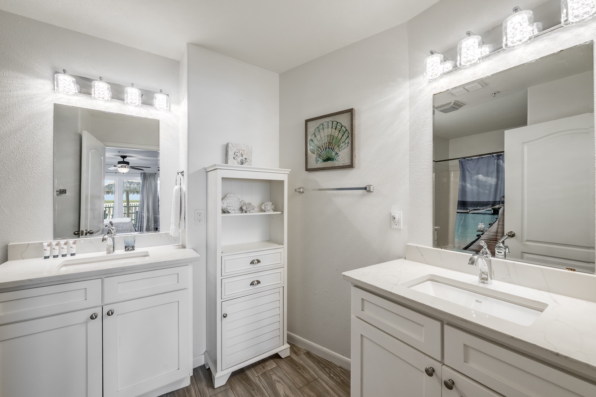 Your spacious dual-vanity bathroom features coastal-inspired décor, elegant white cabinetry, and plenty of counter space for a comfortable morning routine.