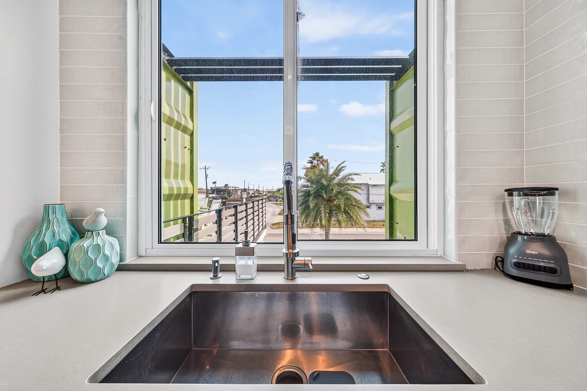 Your kitchen window opens to a breezy coastal street lined with palms and endless blue skies, inviting you to start each day feeling connected to the laid-back beach vibe outside.