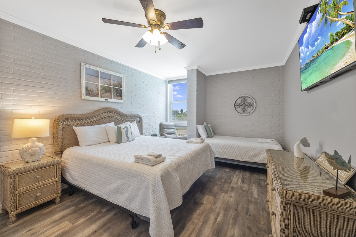 Unwind in your coastal-inspired bedroom featuring comfortable beds, tropical décor, and a ceiling fan to keep you cool during peaceful nights.