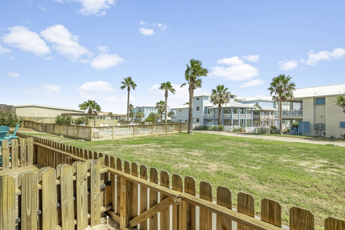 A coastal residential area with palm trees and multi-story buildings under partly cloudy skies.
