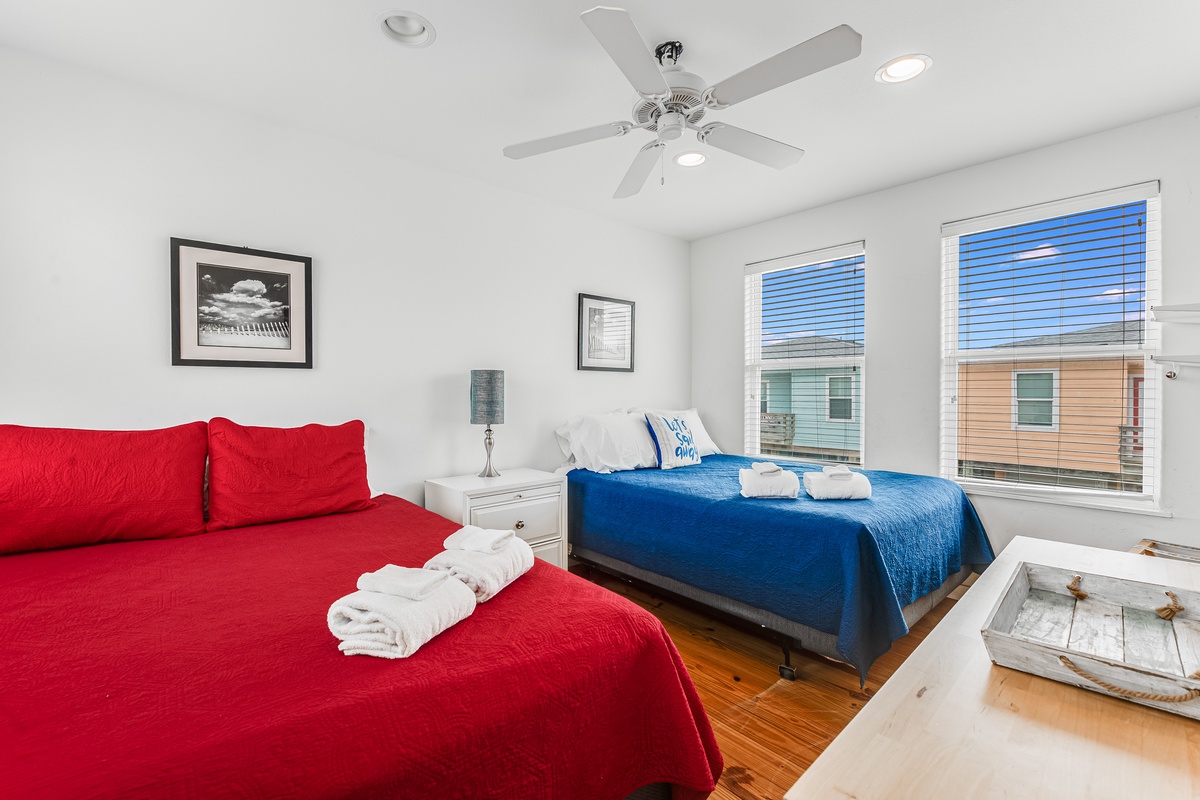 Relax in your bright bedroom with two comfortable beds, fresh towels, and a ceiling fan for perfect comfort.