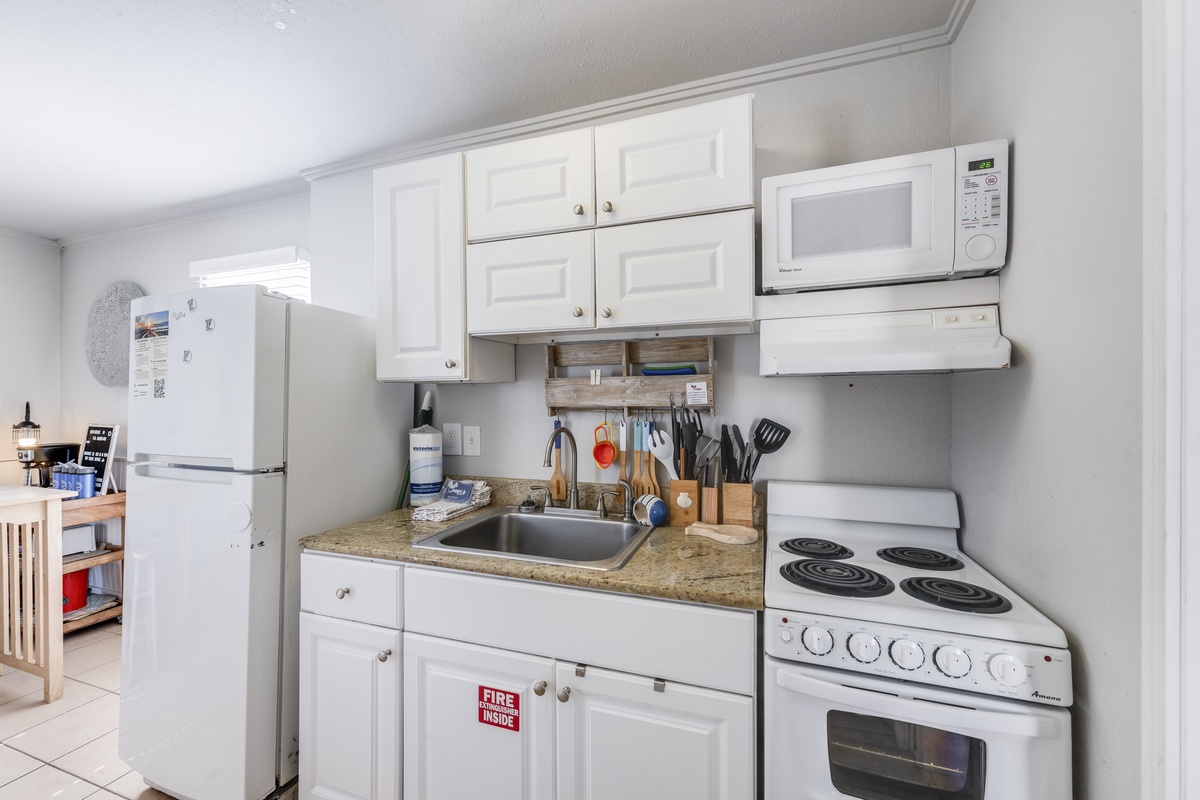 Cook your favorite meals in this fully equipped kitchen with white cabinets, granite countertops, and all essential appliances for a comfortable stay.