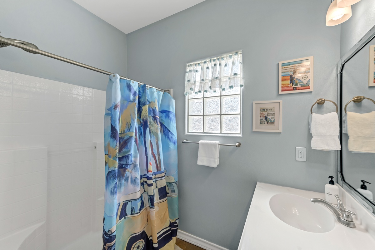 Step into your coastal-themed bathroom, where soft blue walls and beach-inspired artwork create a soothing retreat after sun-filled days.