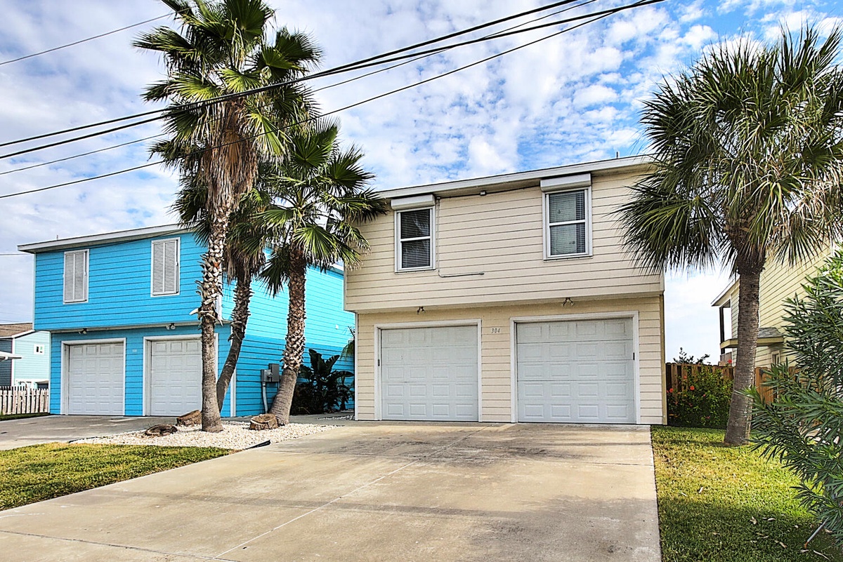 Tropical beach house with palm trees and convenient garage parking in a colorful coastal neighborhood.