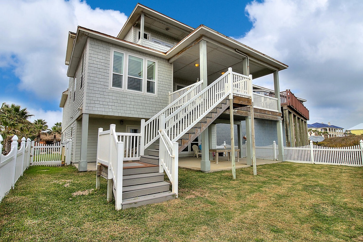 Charming coastal beach house featuring elevated design with covered porches and spacious yard area for relaxation.