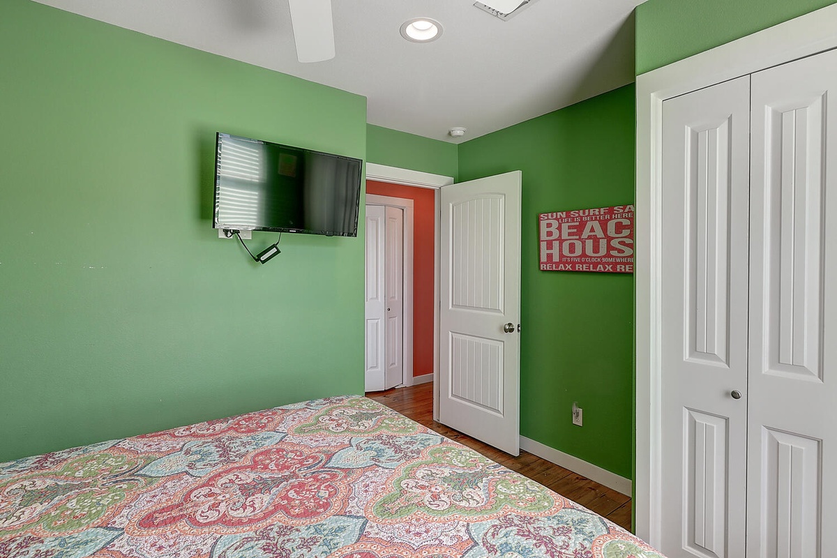 Your bright bedroom features cheerful green walls, flat-screen TV, and beach-themed décor for ultimate relaxation.
