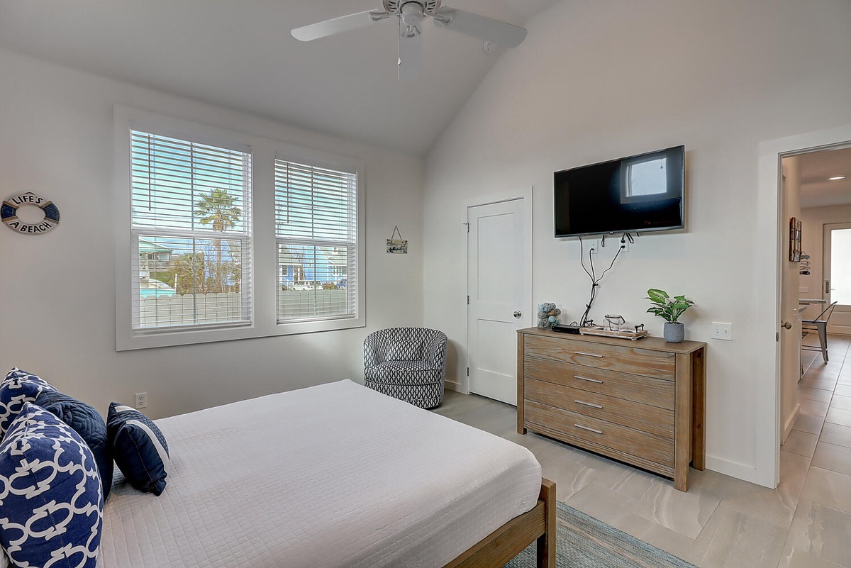 Your bright bedroom features a comfortable bed, coastal decor, and wall-mounted TV for relaxing evenings after exploring.