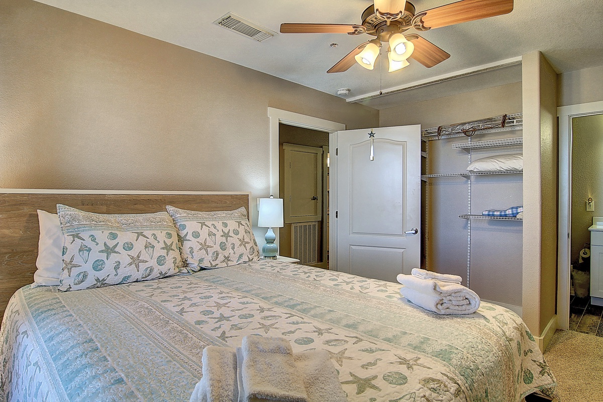 Relax in your serene bedroom with coastal-themed bedding, ceiling fan, and open closet for easy unpacking.