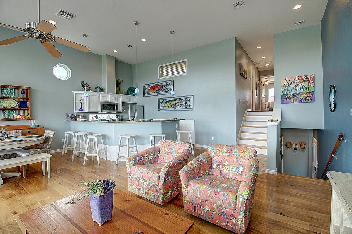 Unwind in your vibrant open-concept living space, where colorful coastal decor meets modern comfort. The fully-equipped kitchen awaits your culinary adventures.