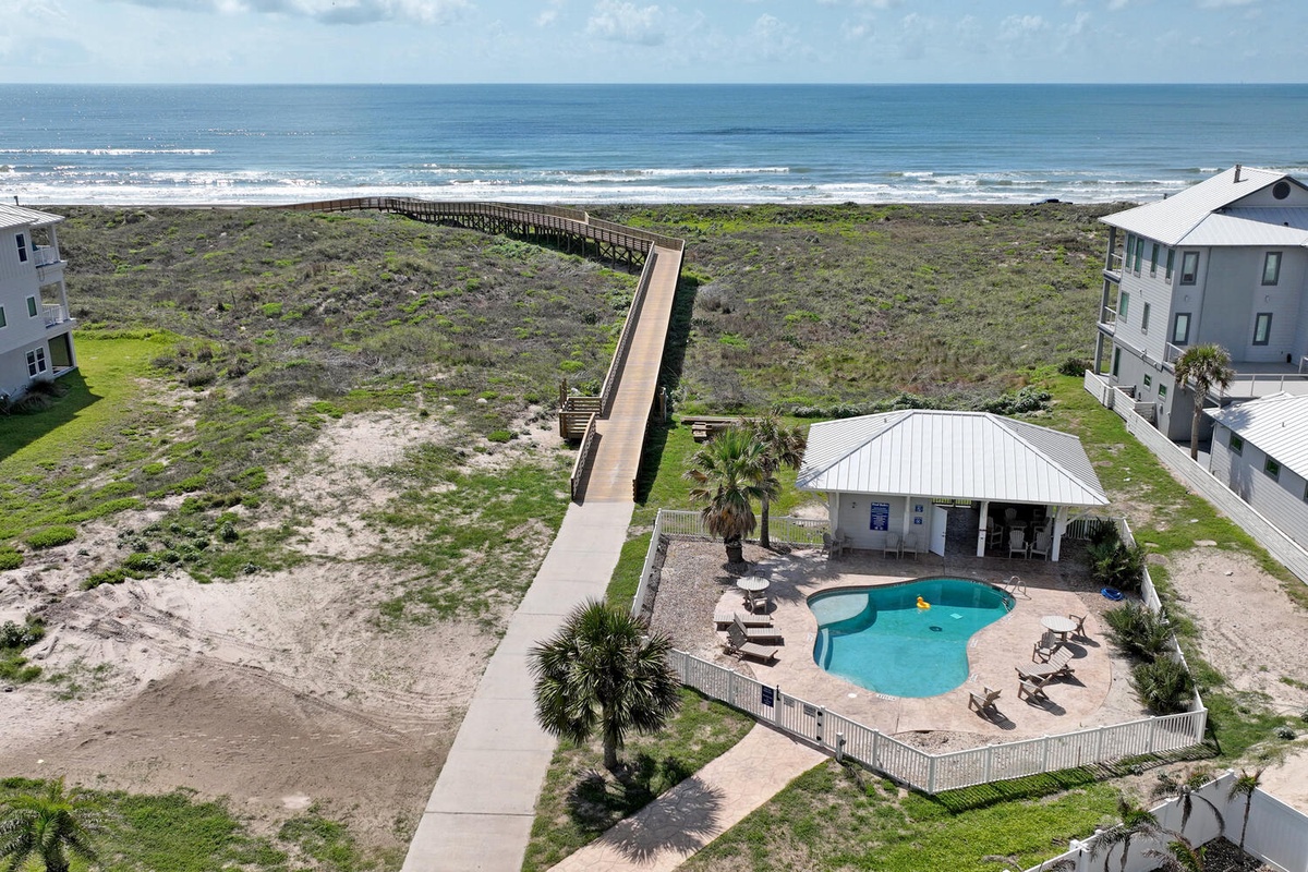 Beachfront property features private pool, boardwalk access to pristine coastline, and coastal home surrounded by natural dunes and palm trees.