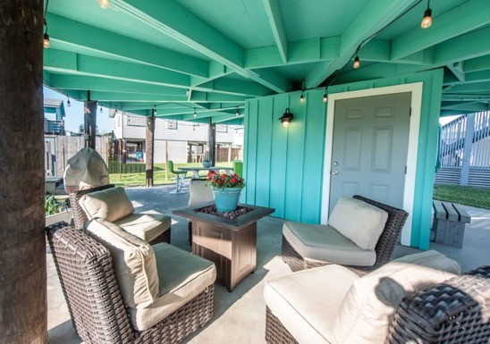 Unwind in your covered outdoor lounge with plush wicker seating and vibrant turquoise beams creating a coastal haven for relaxation.