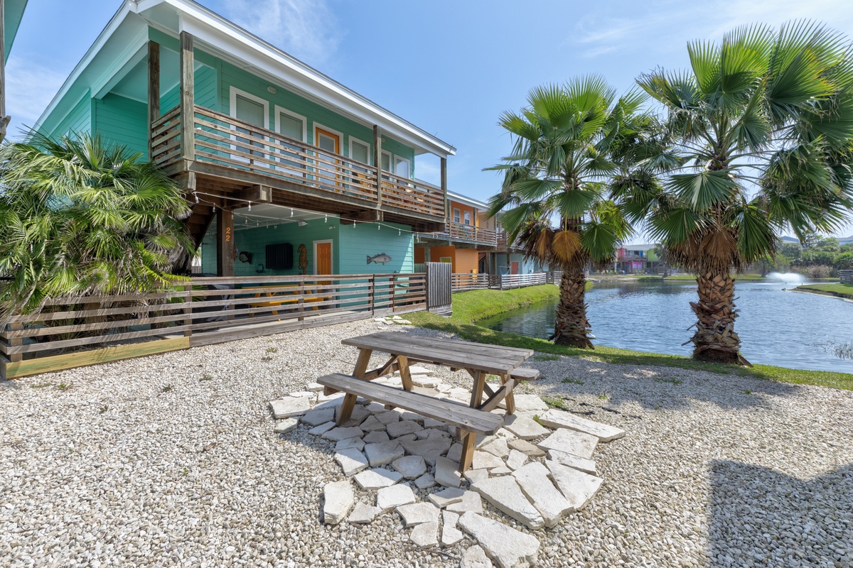 Charming turquoise beach house with waterfront location featuring palm trees, picnic area, and stunning water views for your tropical getaway.