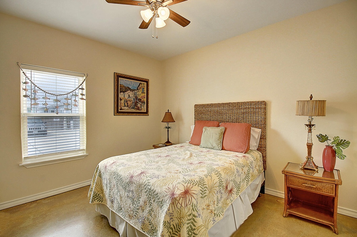 Unwind in your cozy bedroom with tropical bedding, wicker headboard, and gentle ceiling fan keeping you comfortable.