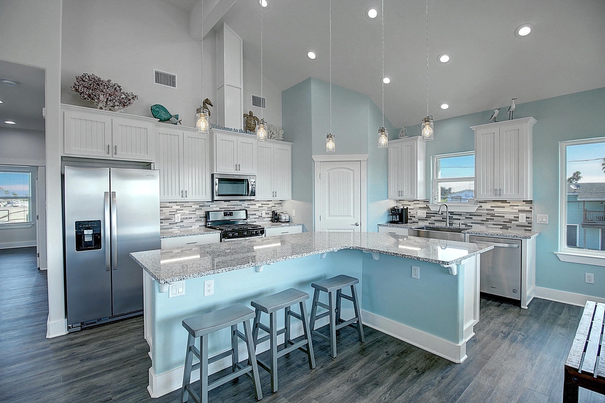 Your modern kitchen welcomes culinary adventures with granite countertops, stainless steel appliances, and coastal-inspired décor beneath sparkling pendant lights.